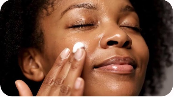 A woman applying a hydrating moisturizer cream to her face as part of a 5-minute hydrating skincare routine for glowing skin.