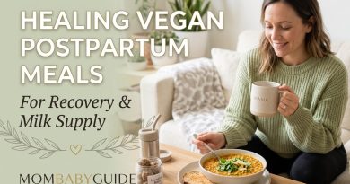A smiling mom sitting on a cozy couch drinking from a "Mama" mug, enjoying a warm bowl of vegan red lentil postpartum stew next to a jar of oat lactation bites. Text overlay reads "Healing Vegan Postpartum Meals For Recovery & Milk Supply" with the MomBabyGuide logo