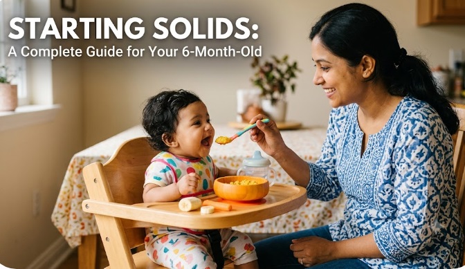 A South Asian mother smiling and feeding her 6-month-old baby girl mashed food from a bowl while the baby sits in a wooden high chair, featuring the text "STARTING SOLIDS: A Complete Guide for Your 6-Month-Old.